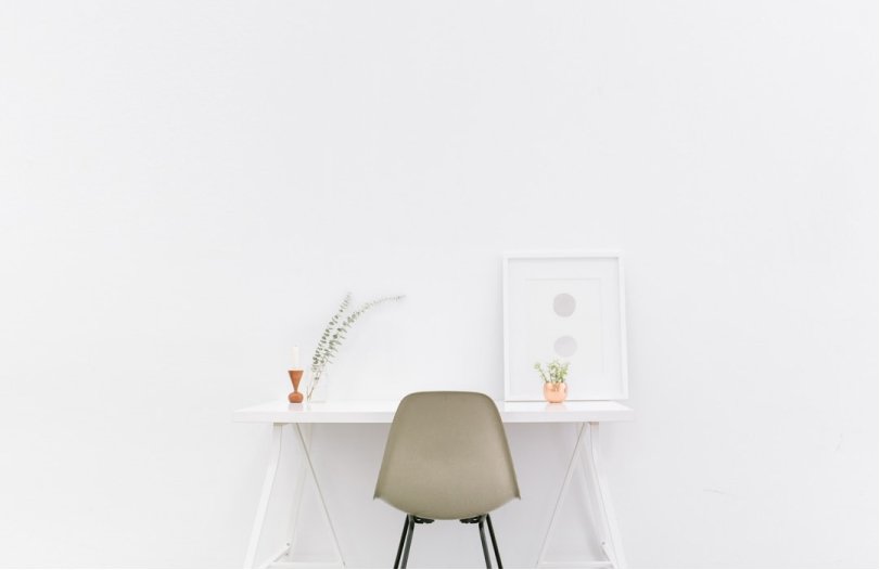a minimalist white table with frame , a small plant display and a brownish chair